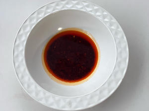 Pour oil-infused chili flakes into a bowl.