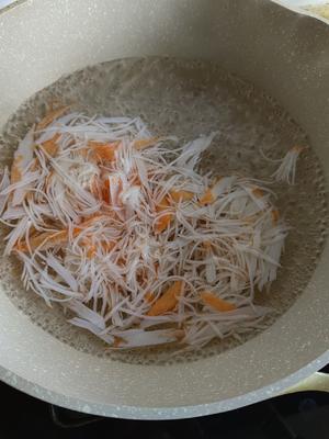 Bring water to a boil in a pot, add the shredded crab sticks, blanch for 30 seconds, then drain.