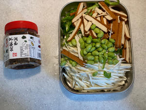 Clean and remove the stems and seeds from the green pepper, then shred it for later use. Peel the outer skin of the young bamboo shoots, rinse them, remove the old roots, and slice them into shreds. I bought peeled soybeans to save time, just rinse them. Cut the dried tofu into shreds as well.