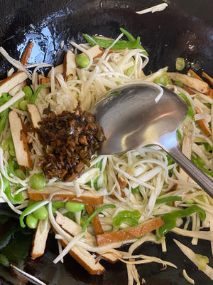 After the shredded young bamboo shoots become tender, add a tablespoon of grandmother's vegetable, a little sugar, and a small amount of light soy sauce. Stir-fry evenly over high heat. If you find it too dry, you can add some water to create a bit of gravy for better taste when served with rice.