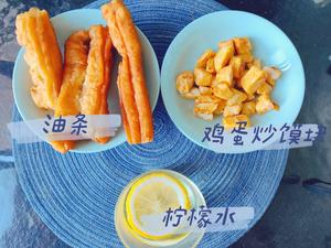 Breakfast of stir-fried egg with flatbread, youtiao, and lemon water.