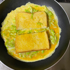 In a frying pan, add a bit of olive oil and pour in the cabbage and egg mixture. Cut a slice of toast in half, then dip each half in the egg mixture before flipping them.