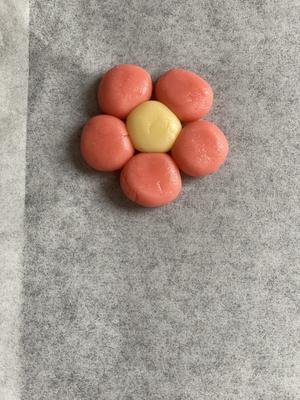 Line a baking tray with parchment paper, then place five red dough balls and one plain dough ball together. Press gently to form petals and shape the flower.