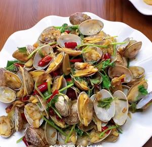 For stir-fried clams, start by heating the pan to release water, then remove and add oil. Sauté ginger, garlic, and dried chilies until fragrant, then add the clams, seasoning with salt, soy sauce, and cumin powder to reduce liquid! Sprinkle with cilantro before serving! Quickly scoop out opened clams to avoid losing the meat!