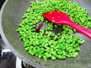 Stir-fry the cowpeas until they change color, then drizzle an appropriate amount of premium soy sauce and salt around the edges of the pan.