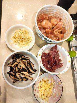 Slice the soaked shiitake mushrooms, mince the garlic, julienne the ginger, and slice the Chinese sausage. Marinate the free-range chicken with rice wine, oyster sauce, soy sauce, cornstarch, salt, and oil for 20 minutes.