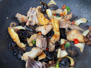 Once the chicken is golden brown, add the ingredients (wood ear mushrooms, hazel mushrooms, chili peppers, vermicelli) and continue to stir-fry over medium-high heat.