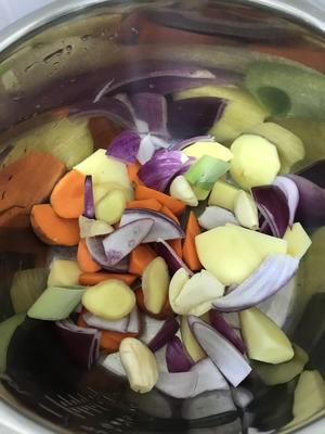 In the electric pressure cooker, lay the chopped ingredients at the bottom, add slices of ginger, smashed garlic, and large pieces of spring onion.