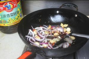 Discard the excess oil, leaving a bit at the bottom. Add the garlic cloves, ginger slices, onions, dried chili peppers, and Sichuan peppercorns to stir-fry until fragrant.