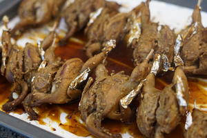 After 25 minutes, take the quails out, flip them over, and brush with a little more honey water.