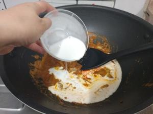 Heat the pot again, adding the remaining 30 grams of butter, followed by the chopped onion. After sautéing slightly, add the curry paste and 2/3 of the coconut milk. Stir and mix, then add a little water to continue simmering.