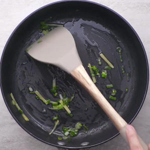 In a hot pan, add oil, chopped green onion, and ginger strips. Stir on low heat to release the aroma.