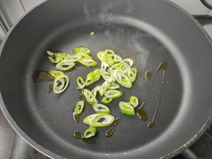 Heat a tablespoon of vegetable oil in a pan, then add chopped scallions and sauté until fragrant.