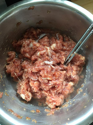 Mix thoroughly, then gradually add the soaked scallion-ginger water in three additions, stirring in one direction until fully absorbed before adding more.