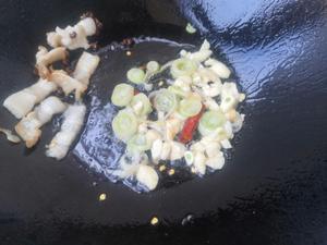 Push the pork to one side of the pan, add garlic, green onion, and chili to stir-fry until fragrant.